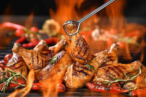 grilled chicken legs and chicken thighs on the flaming grill